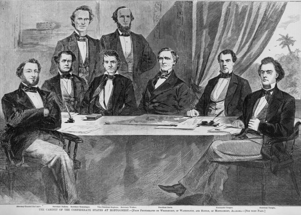 Members of the Confederate States Cabinet. Seated at a table, left to right, are: Judah Benjamin with arms folded and fully bearded. Next to him is Stephen Mallory with a stern expression, vest, and beard; Alexander Stephens seems more comfortable with his jacket wide open; Christopher Memminger sits slightly with his body slanted to his right. He has no beard; Leroy Walker is clean shaven with a widows peak and vest; Robert Toombs is the last person seated. His arm is across his body, and his right arm rests on paperwork with a seal. Behind these men are John Reagan and Jefferson Davis. Davis stands with his left hand tucked behind his back. 