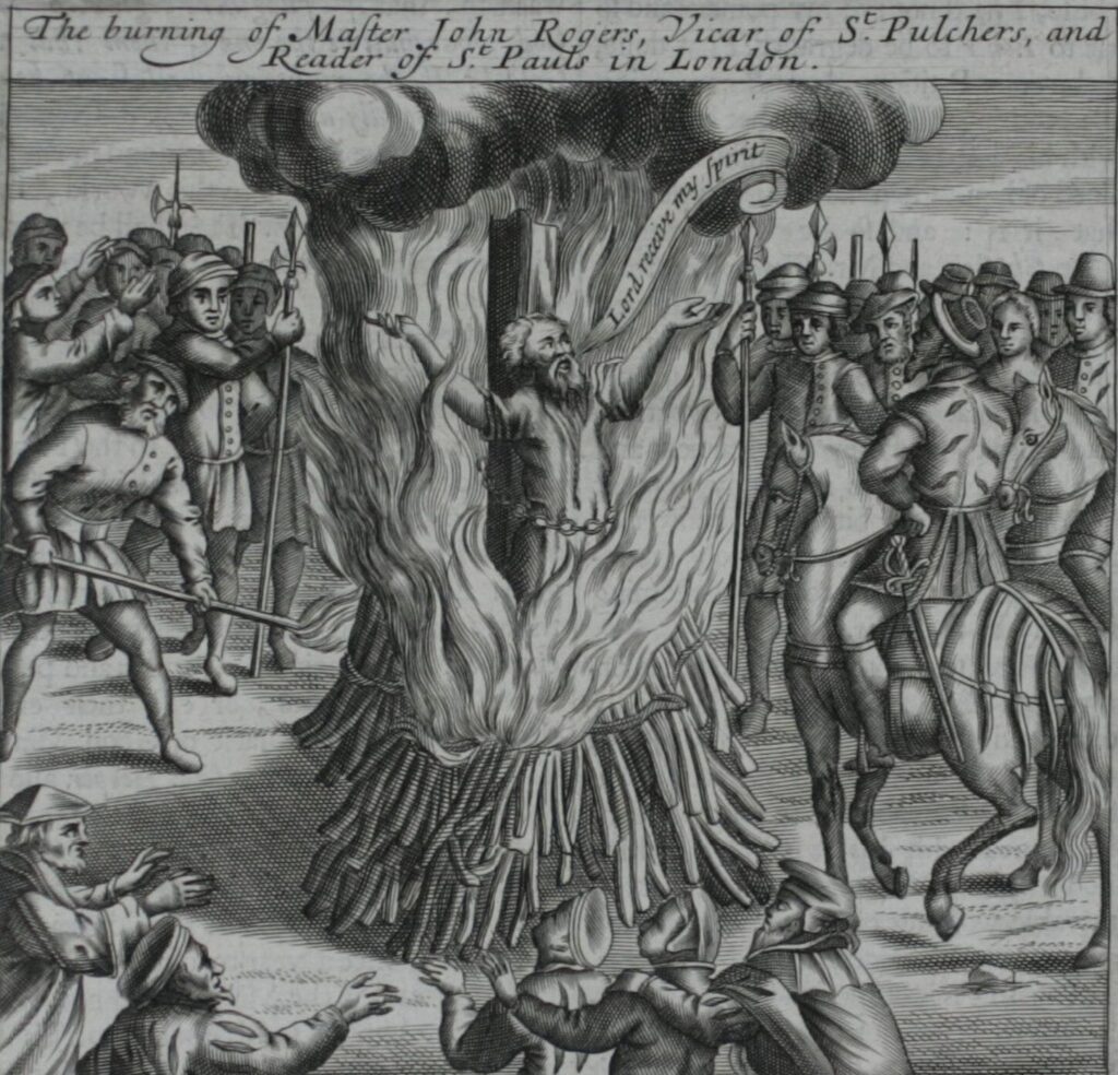 In this black-and-white illustration, across the masthead reads "The burning of Master John Rogers, Vicar of St. Pulchers, and Reader of St. Pauls in London." At the center, John Rogers is shown shackled to a wooden post with flames and smoke rising around him. He utters "Lord receive my spirit" as people look on. This image is a reminder of the consequences of practising a non-established religion.