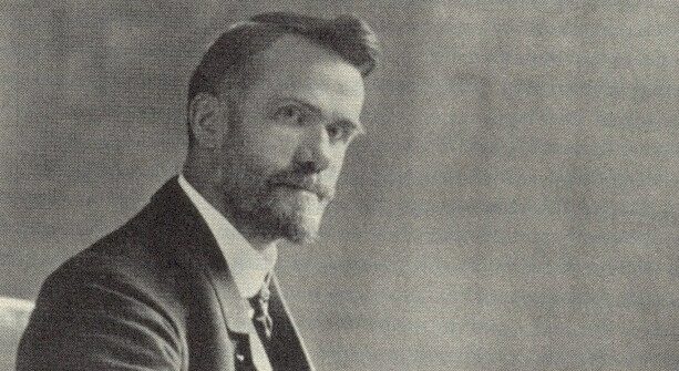Portrait of Walter Rauschenbusch, theologian and Baptist minister, is shown seated in a coat, jacket, and tie, staring directly into the camera. Rauschenbusch preached that religious and social life were intertwined.