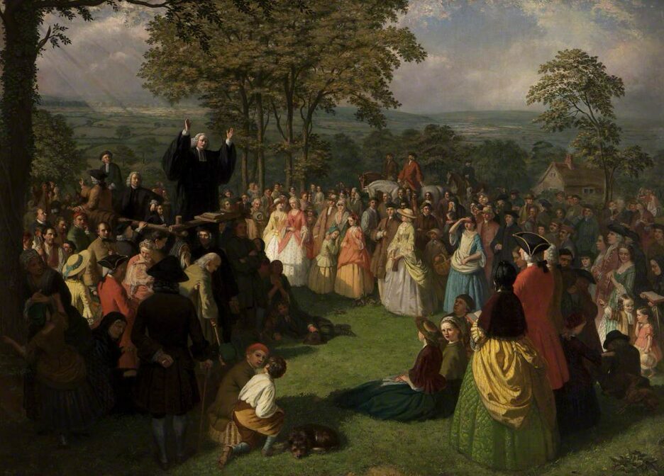 Dark oil painting of George Whitefield preaching to a crowd in a field in Bolton, June 1750, by artist Thomas Walley, 1863. Whitefield stands on the left with outstretched arms and black robes, while people stretch as far as the eye can see. Some are seated, but most stand in their Sunday best clothing and hats.