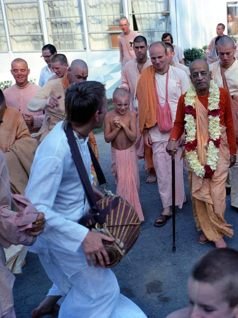 Indian spiritual leader and religious teacher Swami Prabhupada on the top right and students in ISKCON, Potomac, Maryland, US. One student plays the mridanga drums. Other male disciples are seen in traditional shirt and skirt with folds.