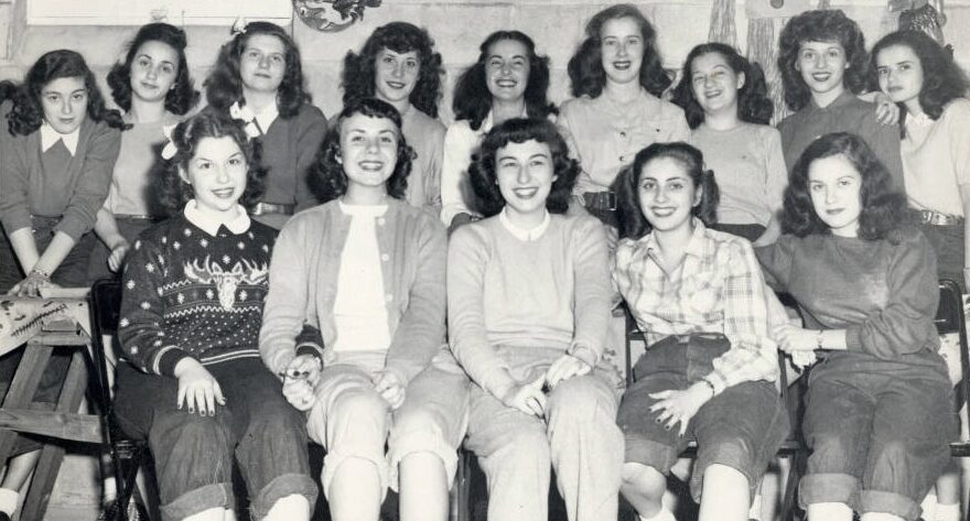 Jewish high school sorority sisters celebrate a Halloween party. The girls are dressed in pants rolled to their knees and shirts with sweaters.